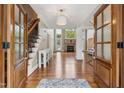 Inviting foyer with hardwood floors, staircase, chandelier, and a glimpse into the living area with fireplace at 55 Fleming Forest Dr, Youngsville, NC 27596