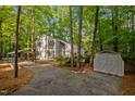 Shot showing the home's exterior, driveway, a carport, and a storage shed amidst lush trees at 568 Piney Mountain Rd, Chapel Hill, NC 27514