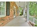 Inviting covered front porch with brick facade, white columns, and access to the front door and windows at 5825 Scalybark Rd, Durham, NC 27712