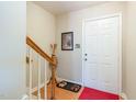 Bright foyer featuring hardwood floors, a white front door, and a staircase with wooden banister at 6922 Saxby Ct, Raleigh, NC 27613