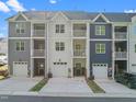 Rear view of three-story townhomes featuring private garages and balconies on each unit, showcasing modern design at 820 Laurel Gate Dr, Wake Forest, NC 27587