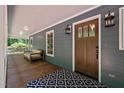 Inviting front porch features a wood door, outdoor seating, stylish lighting, and a beautiful patterned rug at 9625 Collins Creek Dr, Chapel Hill, NC 27516