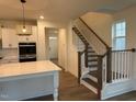 Kitchen with quartz island adjacent to staircase with wood and white trim at 1024 Channel Drop, Zebulon, NC 27597