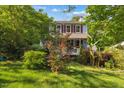 Charming two-story home with red shutters, lovely landscaping, and a lush lawn surrounded by mature trees at 1924 Strebor St, Durham, NC 27705
