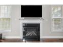Close-up of the fireplace, complete with a TV and decorative mantle, flanked by natural light-filled windows at 200 Heather Brook Cir, Spring Lake, NC 28390