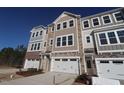 New townhome with attached garage and a mixed material facade of siding and stone under a clear blue sky at 2297 Bay Minette Sta # 536, Apex, NC 27502