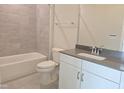 Bathroom features gray tiled walls, tub, white vanity with dark countertop and chrome fixtures at 3026 Freewinds Way # 50, Cary, NC 27519