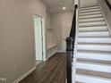 Bright foyer features wood flooring, staircase with dark handrail and access to hall with coat storage bench at 3026 Freewinds Way # 50, Cary, NC 27519