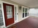 Inviting covered porch with a red front door and warm, wood-look flooring at 3032 Kilarney Ridge Loop, Cary, NC 27511
