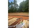 Image of lot under construction with lumber and soil, framed by mature trees, hinting at a private and scenic backyard at 314 Shiloh Way, Mebane, NC 27302