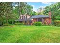 Attractive Tudor-style home with brick accents, and a chimney nestled in a lush green landscape at 502 Hiddenbrook Dr, Durham, NC 27703