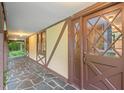 Covered front porch with stone floor tiles leading to an elegant, glass-paned front door and windows at 502 Hiddenbrook Dr, Durham, NC 27703