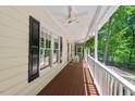 Covered porch with wooden floors, ceiling fans, and picturesque views of lush greenery at 524 Preston Andrews Rd, Bahama, NC 27503