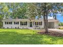 Charming, renovated home featuring a painted brick exterior, mature landscaping, and an attached carport at 5718 Woodcrest Dr, Raleigh, NC 27603