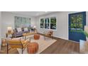 Cozy living room showcasing hardwood floors, a large window, stylish furnishings, and a vibrant blue front door at 5718 Woodcrest Dr, Raleigh, NC 27603