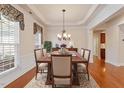 Elegant dining room featuring hardwood floors, decorative molding, and a chandelier, with table set for a formal dinner at 716 Arbor Brook Dr, Cary, NC 27519
