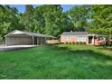 View of a well-maintained front yard with a carport adjacent to the brick house, creating ample parking and curb appeal at 114 Short E St, Hillsborough, NC 27278