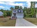Charming two-story home with gray siding, brick stairs, a two-car garage, green lawn, and tree-lined background at 115 Parkers Gate Dr, Youngsville, NC 27596