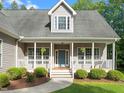 Welcoming front porch with white railings, hanging plants, landscaping and a walkway to the front door at 128 Madison Ct, Siler City, NC 27344