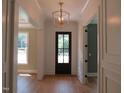 Bright foyer with elegant chandelier, hardwood floors, and detailed trim work throughout at 1444 Old Apex Rd, Cary, NC 27513