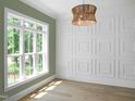 Bright living room featuring a decorative light fixture, trim accent wall, and large window at 1444 Old Apex Rd, Cary, NC 27513