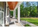 Inviting covered porch with wood ceiling, white columns and rocking chairs at 165 Alpine Rd, Moncure, NC 27559