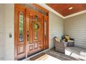 Inviting front porch with a wooden front door, sidelights, and comfortable seating area at 208 Bellagio Dr, Apex, NC 27539