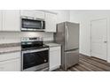 Close-up of modern kitchen appliances, stainless steel refrigerator and oven with granite countertop at 2107 Glen Crossing Dr, Durham, NC 27704