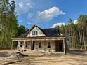 New construction home featuring a covered porch and surrounded by lush trees at 328 Green Pines Estates Dr, Kenly, NC 27542