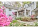 Inviting white home with a spacious covered porch, complemented by colorful flowering bushes and stone pathway at 4 The Gln, Chapel Hill, NC 27514