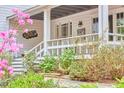 Close-up of a cozy covered front porch with white railings, surrounded by lush landscaping and flowering trees at 4 The Gln, Chapel Hill, NC 27514