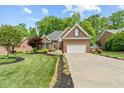 Charming brick home featuring a manicured lawn, attached two car garage, and lush landscaping at 480 Whitt Ave, Burlington, NC 27215