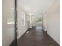 Inviting hallway with dark wood floors, neutral walls, and crown molding, leading to bright, airy rooms at 556 Lemon Daisy Ln, Knightdale, NC 27545
