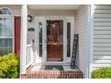 Close-up of the front door and entry featuring a welcome sign and brick-laid porch at 7109 Spanglers Spring Way, Raleigh, NC 27610