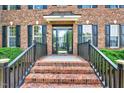 Inviting front entrance with brick steps, black railings, glass door, and manicured shrubbery at 1009 Sarazen Dr, Clayton, NC 27527