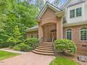 A brick home's arched doorway with a brick walkway and lush landscaping creates a welcoming approach at 1428 Gray Bluff Trl, Chapel Hill, NC 27517