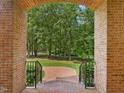 View through arched brick entryway of the front yard, lawn and surrounding trees at 1428 Gray Bluff Trl, Chapel Hill, NC 27517