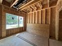 Unfinished room featuring exposed wooden framing, a window, and wood paneling on the floor at 1521 Sunrise Ave, Raleigh, NC 27608