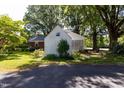 View of the backyard with the brick home and white storage shed surrounded by mature trees and green lawn at 210 S Hughes St, Apex, NC 27502
