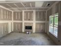 Spacious living room with fireplace installation and natural light from windows under construction at 214 Green Pines Estates Dr, Kenly, NC 27542