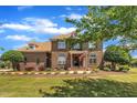 Traditional brick home with manicured landscaping, an American flag, and an arched window above the front door at 296 Shoreline Dr, Princeton, NC 27569