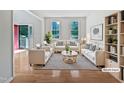 Bright living room with hardwood floors, white sofas, striped rug, and open entrance at 3705 Cassaro Ln, Zebulon, NC 27597