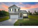 Charming two-story home featuring stone accents, a welcoming front porch, attached garage, and a well-manicured lawn at 482 Olivia Crossing Ct, Four Oaks, NC 27524