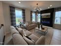 Inviting living room featuring a modern fireplace, stylish light fixture, plush seating, and large windows with scenic views at 5906 Dunzo Dr, Raleigh, NC 27617