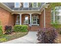 Inviting front porch with brick steps, rocking chairs, white columns, and lovely garden at 708 Mill Pointe Way, Elon, NC 27244