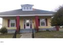 Inviting single-story home showcases a classic yellow exterior, complemented by red support columns, and a quaint dormer at 1007 Grace Ave, Burlington, NC 27217