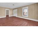 Cozy living room featuring beautiful floors, a large window with blinds, and an open doorway to another room at 1007 Grace Ave, Burlington, NC 27217