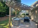 Backyard outdoor kitchen featuring a stone base, wooden pergola, built in sink and a grill at 1021 Golden Star Way, Wake Forest, NC 27587