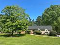 Traditional home featuring a well-manicured lawn and lush green trees at 106 Chariot Dr, Sanford, NC 27330