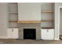 Cozy living room fireplace with gray tile surround, built-in shelves, and cabinets for storage at 118 Sanderway Dr, Chapel Hill, NC 27516